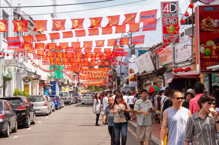 Kleurrijke marktstraat in Maleisië met rode Chinese lampions en vlaggen, drukke sfeer met toeristen en lokale bewoners, winkels en eetkraampjes, rijke cultuur en levendige omgeving.
