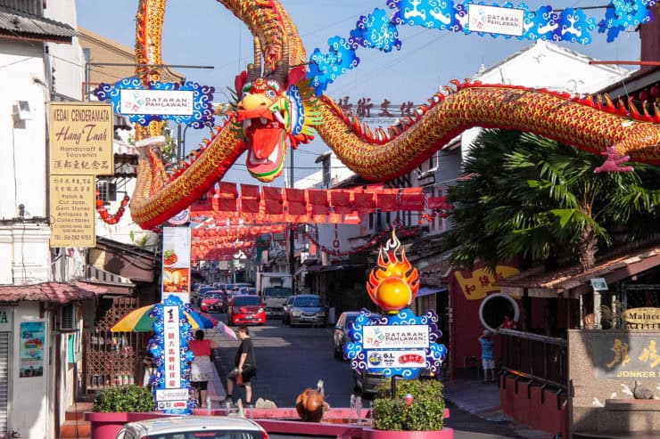 Kleurrijke Chinese drakensliert op straat in Malakka, Maleisië, tijdens een festival, met traditionele decoraties, kleurrijke banners en druk verkeer op de achtergrond.