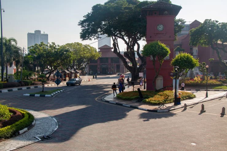 Kleurrijk stadsplein in Kuala Lumpur met historische klokketoren, omgeven door groene bomen en moderne gebouwen, ideale locatie voor toeristen en reizigers die Maleisië willen ontdekken.