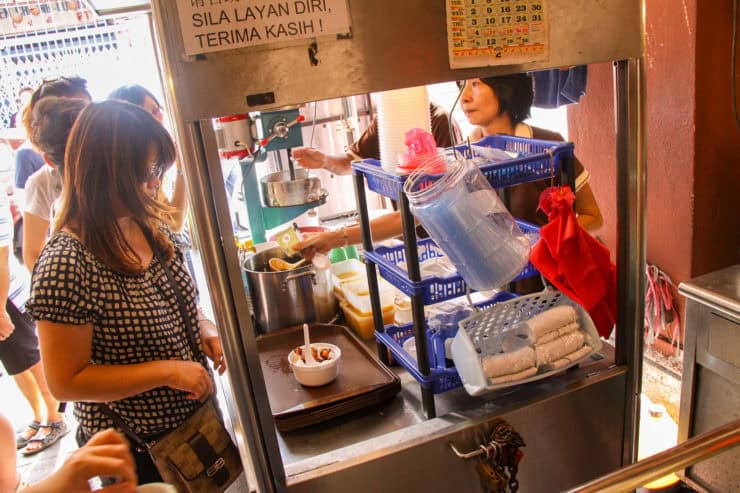 Gezellige streetfood kraam in Maleisië met lokale delicatessen en vriendelijke verkopers voor ultieme culinaire ervaring.