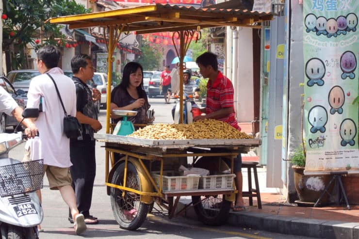 Heetste straatkraam in Maleisië verkoopt krokante snacken, omringd door lokale klanten en voorbijgangers, kleurrijke stadssfeer, culturele marktbeleving, typisch Maleisische streetfood cultuur.
