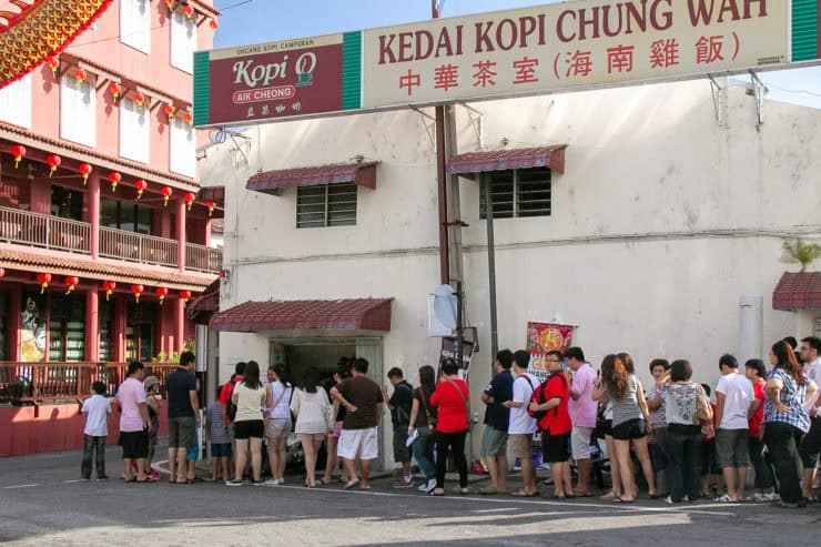 Alinea 2: Lange rij wachtende mensen voor een Chinese restaurant, mogelijk tijdens een feest of speciale gelegenheid in een stadscentrum.