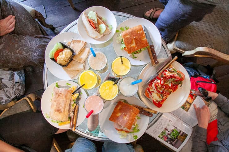 Gezellig etentje met diverse sandwiches en drankjes, typisch Malinese maaltijd met vers fruit en knapperig brood op een ronde tafel, ideaal voor een culturele ervaring in Maleisië.