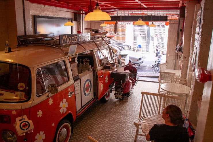 Gezellige koffiehoek in een kleurrijk, vintage Volkswagen busje met bloemmotief, ideaal voor ontspanning en hapjes tijdens een maleisië-reis of toeristische stop.
