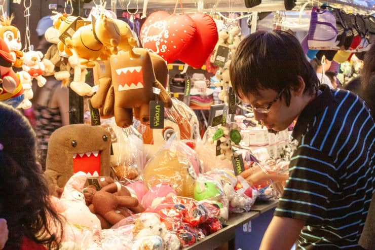 Kleurrijke souvenirwinkel met Domo-kun en andere plush toys, vrolijke kussens en accessoires op een markt in Maleisië.