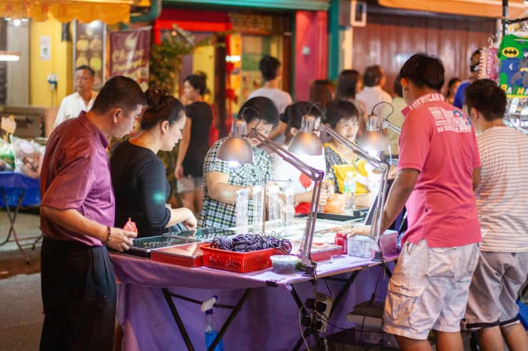 Vrolijk avondmarkt in Maleisië met diverse streetfood stands en bezoekers, kleurrijke sfeer, lokale delicatessen en shopping ervaring op een populaire toeristische locatie.