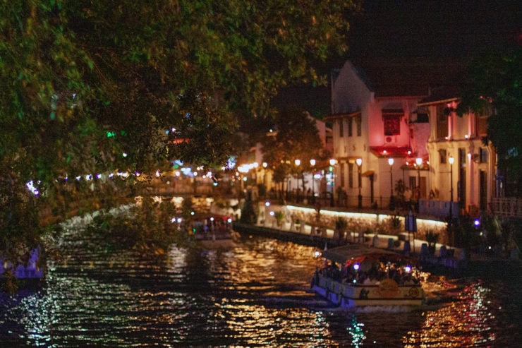 Kleurrijk verlichte rivier met gezellige boottochten en historische gebouwen in Maleisië, perfect voor een romantische avond en het ontdekken van de veelzijdigheid en cultuur van het land.