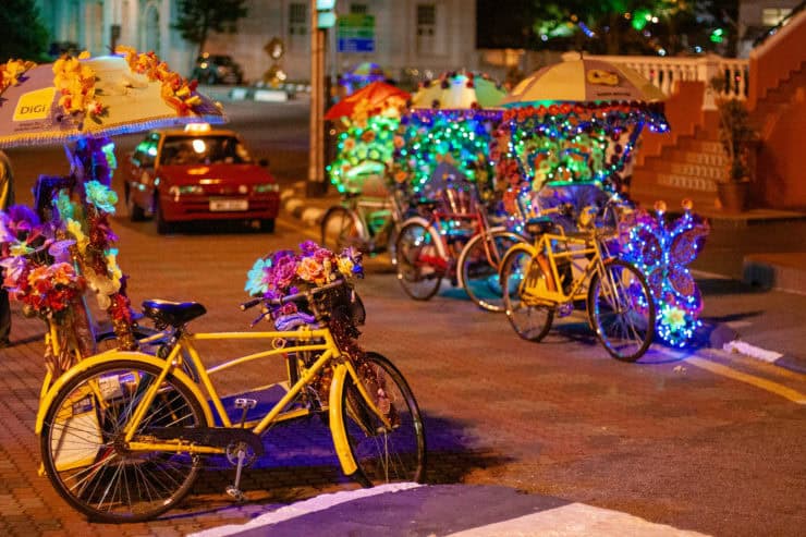 Fiets met bloemenversiering en verlichte pedicabs voor toeristisch vermaak in Maleisië tijdens het avondeten.