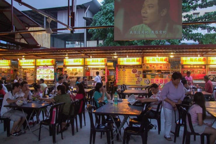 Gezellige avondmarkt in Maleisië met diverse eetkraampjes en bezoekers genieten van straatvoedsel in een bruisende sfeer.