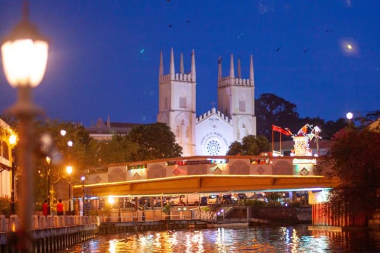 Kerk in George Town, Penang bij avond met verlichte pier, waterreflecties en kleurrijke festival-verlichting, symbool van veelzijdig Maleisië en rijke cultuur.